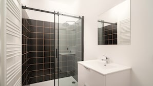 A modern bathroom with a glass shower enclosure, a white sink, and a mirror. - Very Large Central Station 3br/14p Apartment (Antwerp)