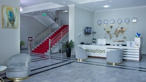 Un área de recepción con un mostrador, una escalera y un mapa del mundo en la pared.