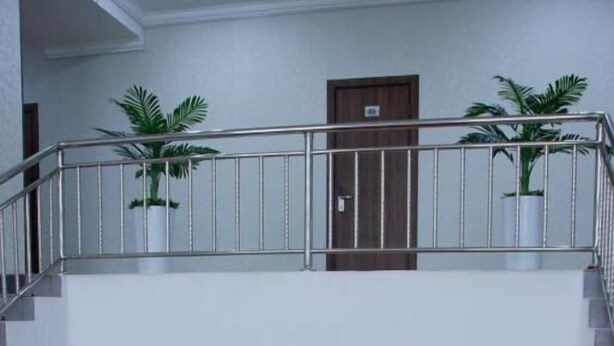 Un vestíbulo de hotel de varios niveles con escalera, zona de estar y plantas en macetas.