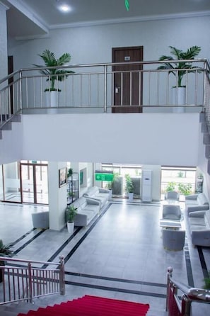 Un hall d’hôtel à plusieurs niveaux, doté d’un escalier, d’un espace salon et de plantes en pot.