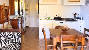 A kitchen with white cabinets, a dining table with chairs, a zebra-patterned sofa, and a wooden cabinet with a mirror. - CN043 - Cesenatico, four-room apartment facing the sea with a panoramic terrace (Cesenatico)