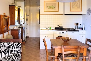 Una cocina con armarios blancos, una mesa de comedor con sillas, un sofá estampado con diseño de cebra y un mueble de madera con espejo.