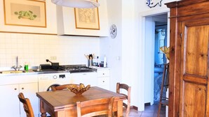 A kitchen with a wooden table, chairs, and a stove. - CN043 - Cesenatico, four-room apartment facing the sea with a panoramic terrace (Cesenatico)