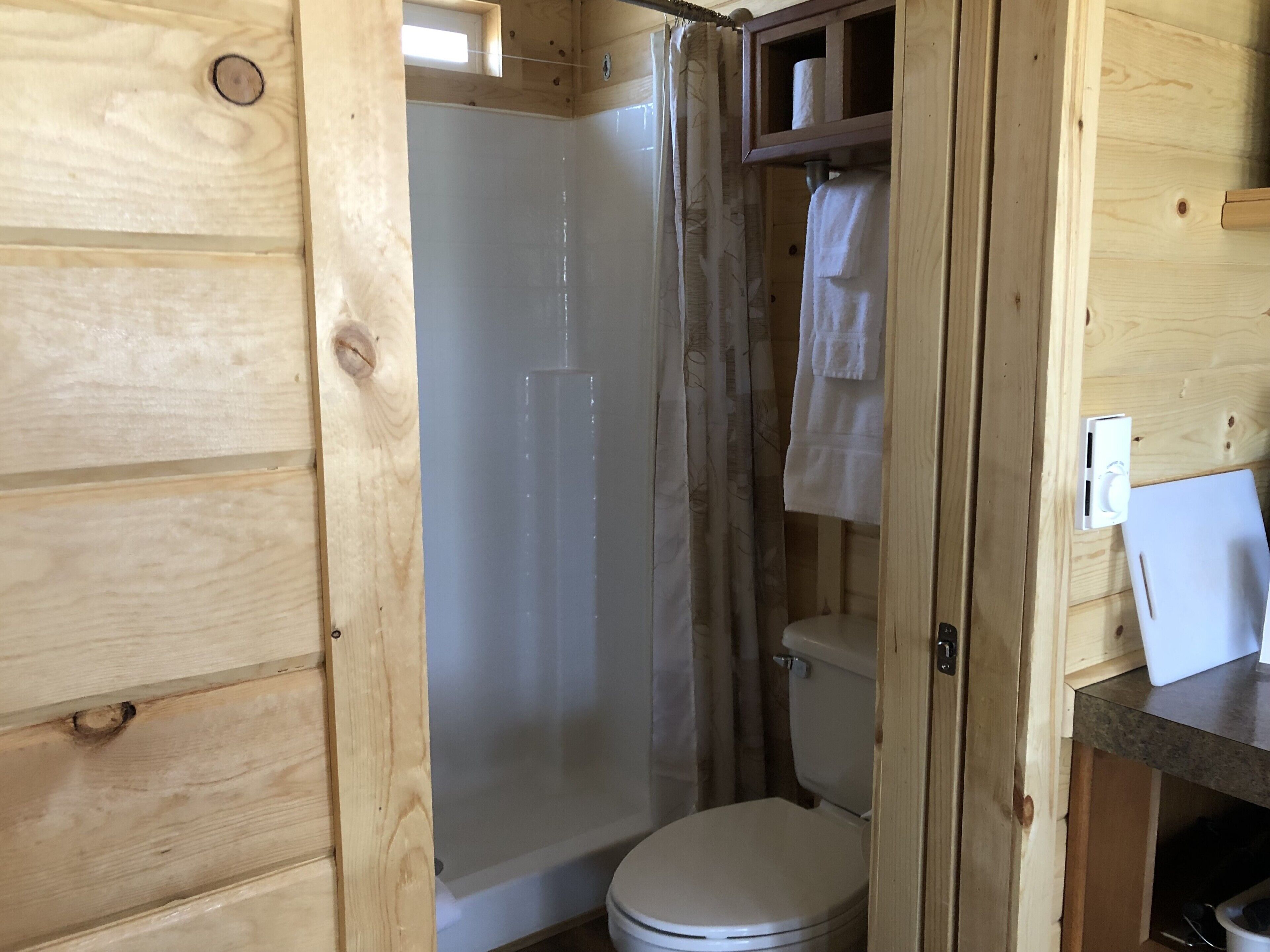 Ein Badezimmer in einer Holzhütte mit Dusche, Toilette und Handtuchhalter.