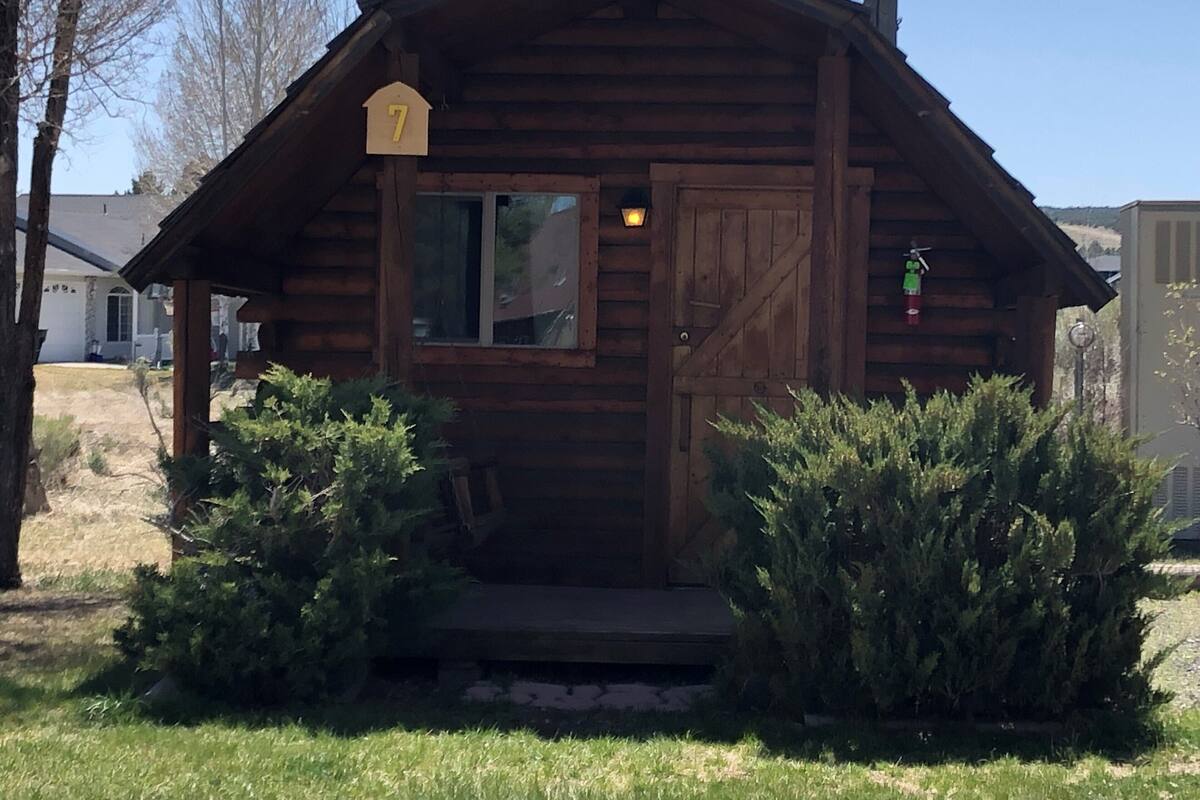 Una cabaña de madera con un letrero con el número 7, una ventana y una puerta.