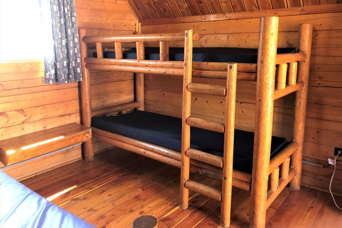 Una habitación con dos camas literas de madera, una ventana y una cortina.