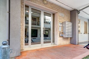 Una entrada de edificio con puerta de vidrio, buzón y un poste de seguridad metálico.