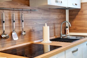 Una cucina con mobili in legno, un lavello in acciaio inossidabile e utensili appesi a un espositore.