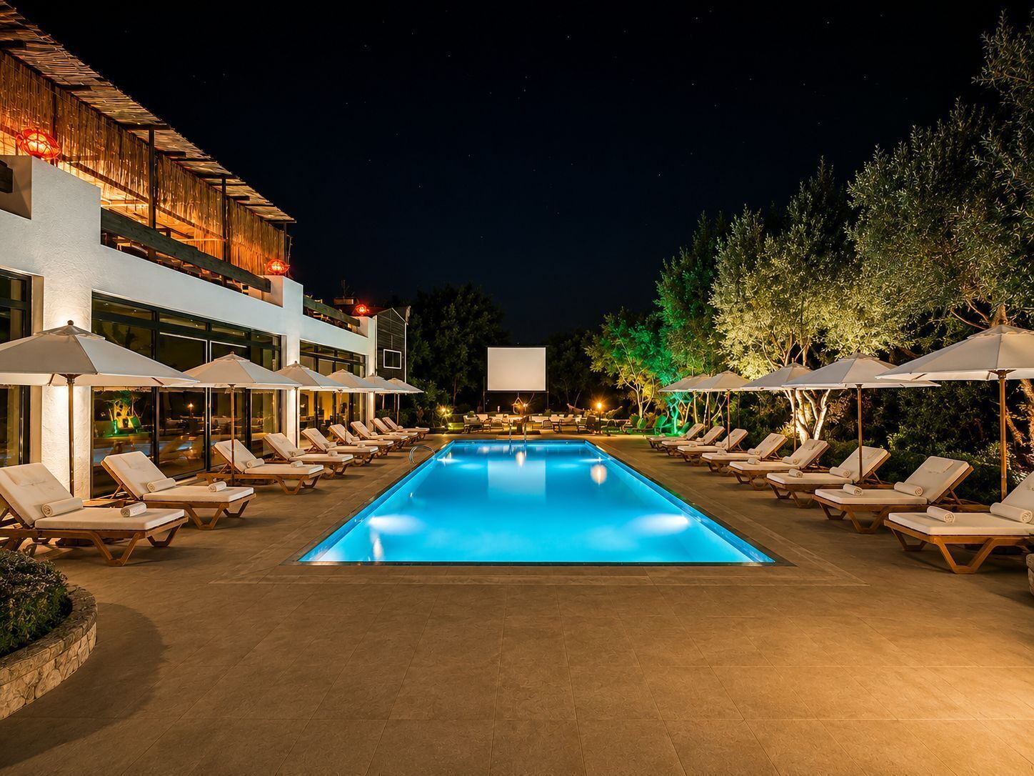 A swimming pool with lounge chairs and umbrellas, surrounded by a building with a modern design.