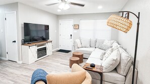A modern living room with a ceiling fan, a sofa, a TV, and a floor lamp.