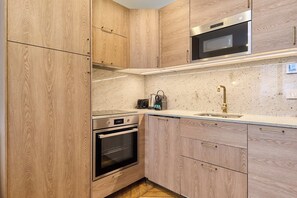 Eine Küche mit Holzschränken, Edelstahlgeräten, einer Spüle und einer Arbeitsplatte.