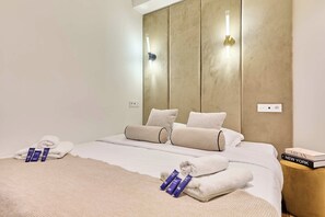 Ein Hotelzimmer mit Bett, Handtüchern, Pflegeprodukten und einem Nachttisch mit einem Buch.