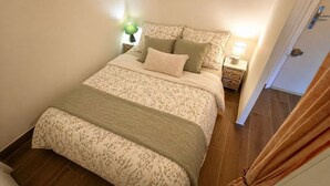 Een slaapkamer met een bed, nachtkastjes, een lamp en een deur.