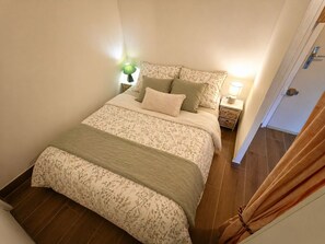 Ein Schlafzimmer mit Bett, Nachttischen, einer Lampe und einer Tür.