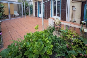 Une terrasse avec une chaise, un petit jardin et une maison dotée d’une porte coulissante.