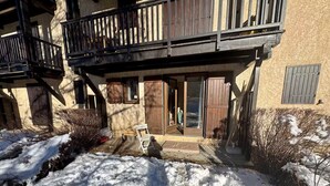 Ein Gebäude mit einem Holzbalkon, einer Glastür und einem verschneiten Gelände.