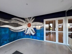 Un interior moderno con un mural único en la pared, una puerta de cristal de entrada y un respiradero en el techo.