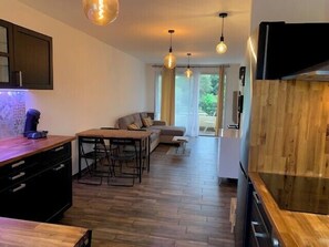 A modern kitchen with wooden cabinets, a dining table with chairs, a sofa, and pendant lighting. - Beautiful 45 m² apartment with balcony in Nice (Nice)