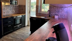 Una cocina moderna con armarios oscuros, encimera de madera y salpicadero con diseño.