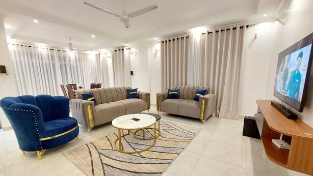 Un salon moderne avec un canapé, un fauteuil, une table basse et un téléviseur.
