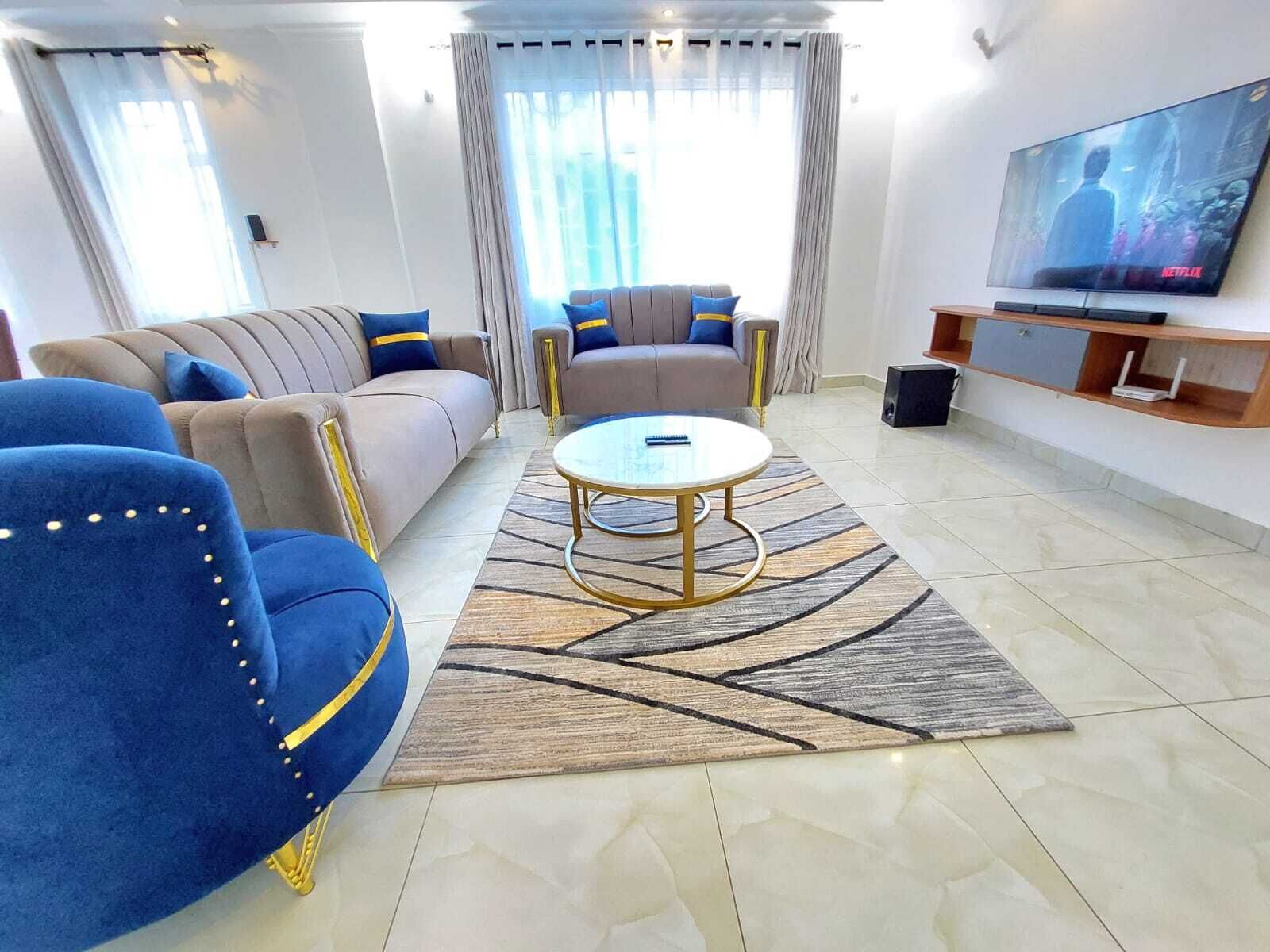 Ein modernes Wohnzimmer mit einer Couch, Sesseln, einem Couchtisch und einem Fernseher.