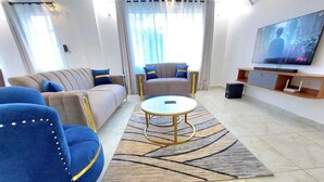 Un salon moderne avec un canapé, des fauteuils, une table basse et un téléviseur.
