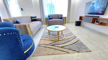 Ein modernes Wohnzimmer mit einer Couch, Sesseln, einem Couchtisch und einem Fernseher.