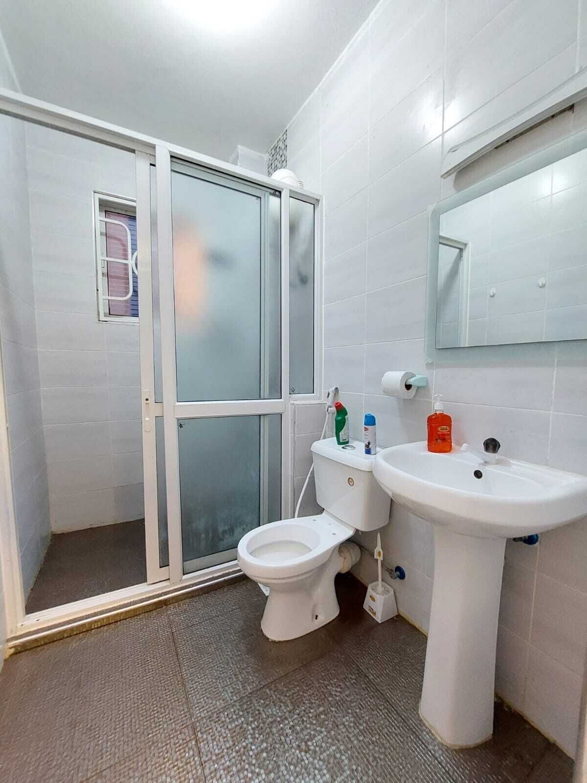 Ein Badezimmer mit Toilette, Waschbecken, Spiegel und Duschbereich.
