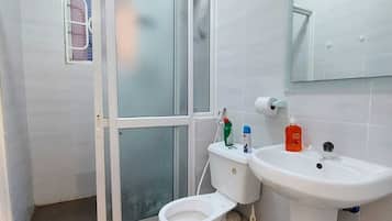 Ein Badezimmer mit Toilette, Waschbecken, Spiegel und Duschbereich.