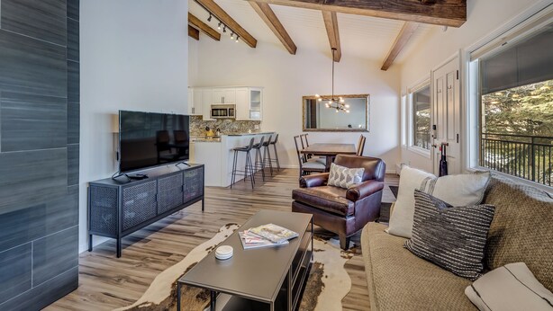 A modern living room with a TV, sofa, and dining area. - Ski In, Modern, Cozy Condo on Aspen Mountain - 1 Block from Gondola & Town (Aspen)