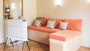 Una habitación con cama, cómoda, espejo y lámpara de pared.