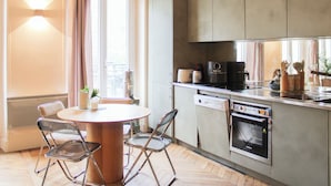 Una cocina compacta con comedor, horno empotrado y ventana con cortinas.