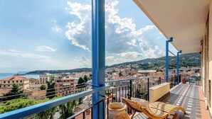 Un balcon donnant sur une ville côtière, avec une table et une chaise.