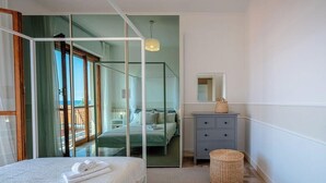 Une chambre à coucher avec un lit, une commode, un miroir et une vue à travers une porte vitrée.