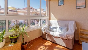 A room with a large window, a sofa, and potted plants. - 'Nomad House' Apartment with Shared Pool, Wi-Fi, and Air Conditioning (Gran Alacant)