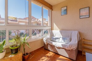 A room with a large window, a sofa, and potted plants. - 'Nomad House' Apartment with Shared Pool, Wi-Fi, and Air Conditioning (Gran Alacant)