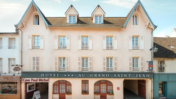 Ein Hotel mit einer klassischen Fassade, zahlreichen Fenstern und einem Schild mit der Aufschrift 'HOTEL AU GRAND SAINT JEAN'.