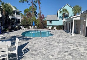 Une piscine avec des chaises longues et un espace patio couvert.