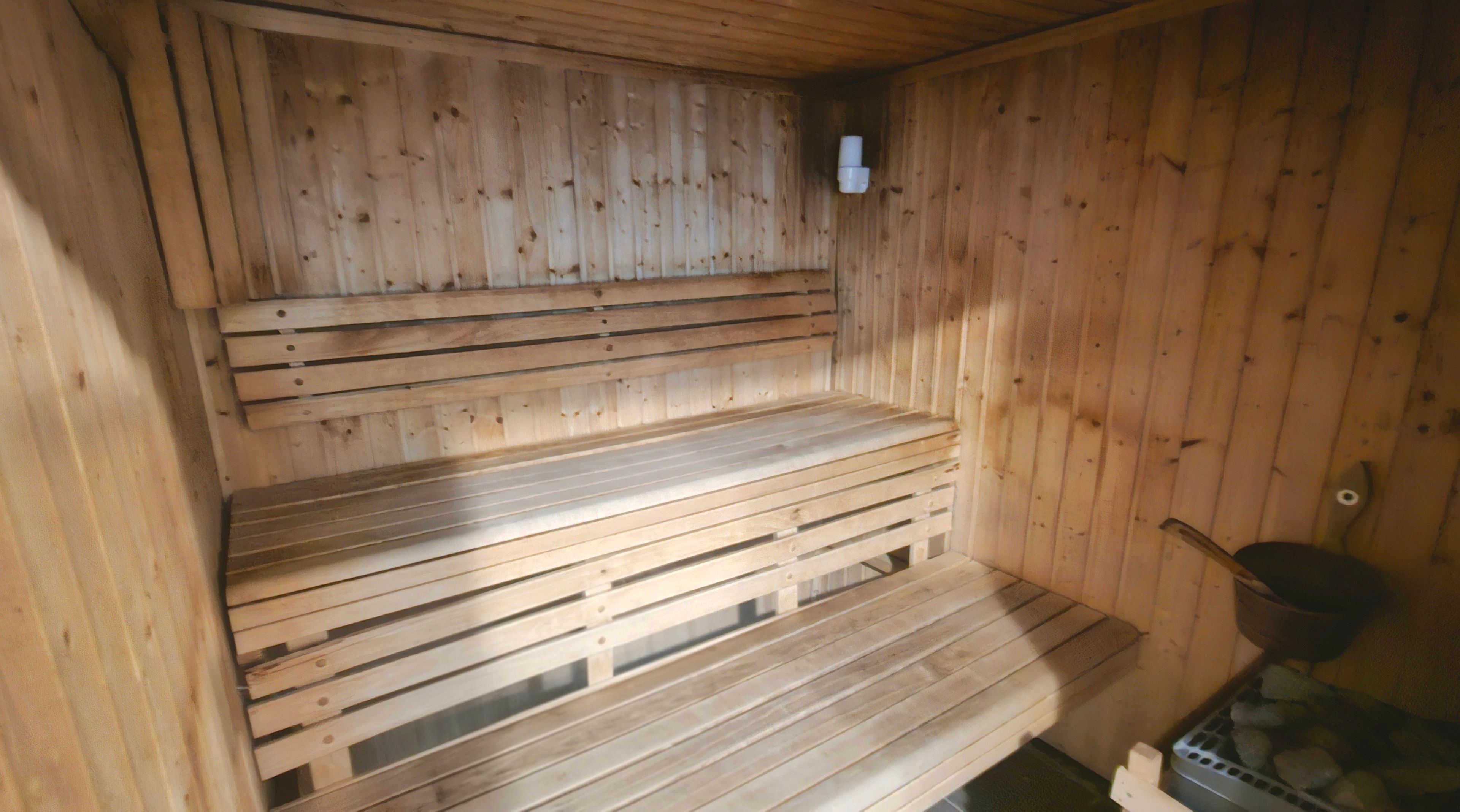 A sauna with wooden benches and a small heater.