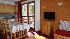 Un intérieur en bois comprenant une table à manger, des chaises, un téléviseur et un canapé.