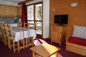 Ein Holzinterieur mit einem Esstisch, Stühlen, einem Fernseher und einer Couch.
