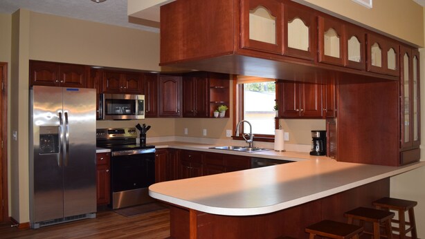 A kitchen with wooden cabinets, stainless steel appliances, and a central island with stools.