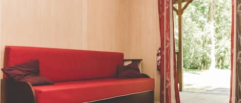 A red sofa with dark wooden legs in a room with wooden walls and a wooden floor.