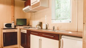 A compact kitchen with a microwave, stove, coffee maker, and a refrigerator.