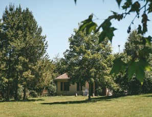 Una casa pequeña con techo de tejas, rodeada de césped y árboles.