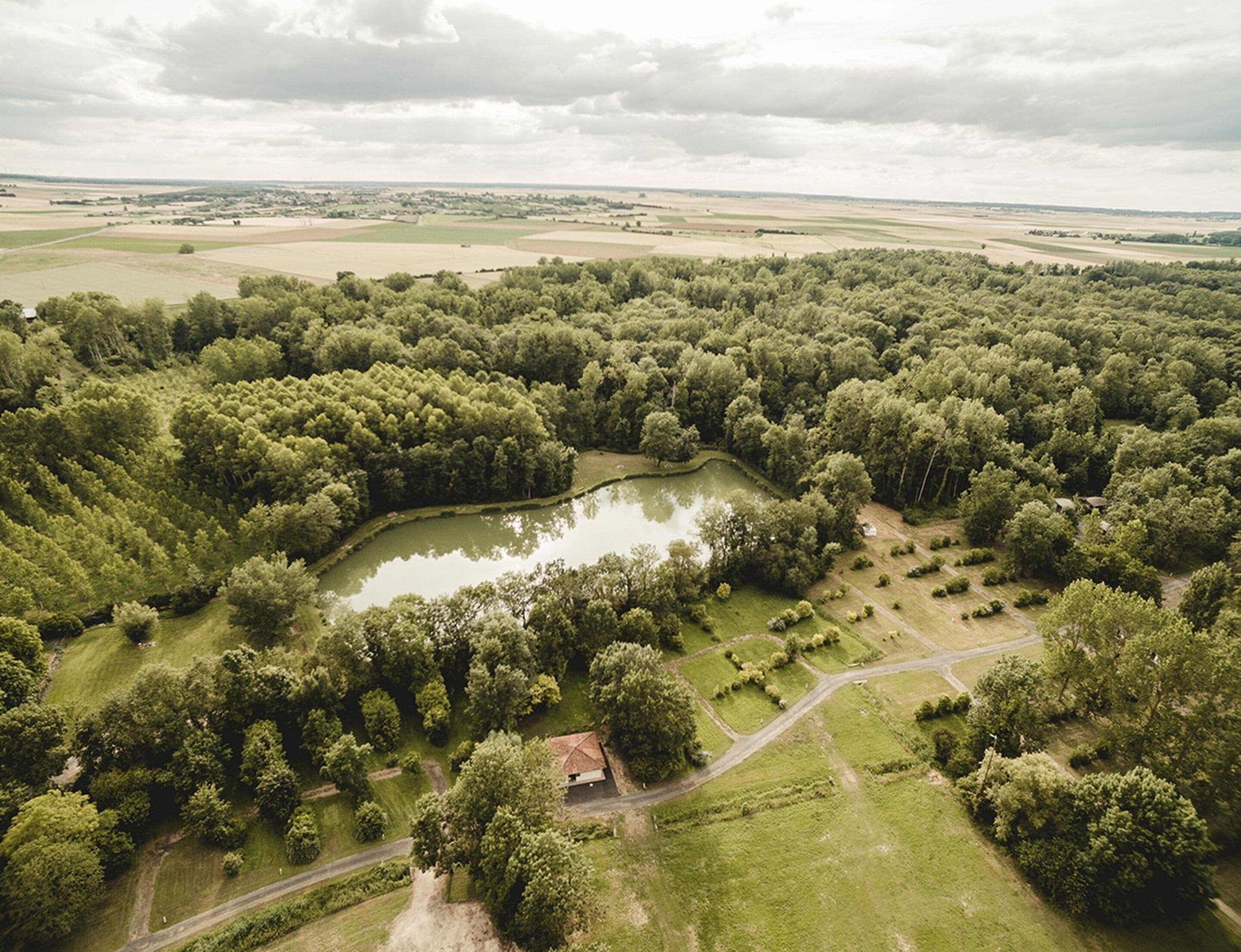 Oversigtsbillede af et landligt landskab med en sø, tæt skov og åbne marker.