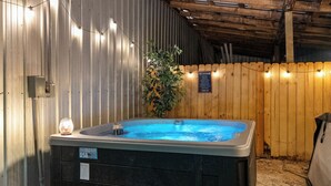 A hot tub with a wooden fence and string lights, surrounded by a corrugated metal wall. - Direct Access to Brimstone Trails & River. Hot Tubs. Fire Pits. Pets (Huntsville)