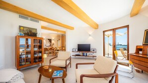 A spacious living room with wooden furniture, a television, and a view of the sea. - Villa 'Relax Cabrera Miramar' (Colònia de Sant Jordi)