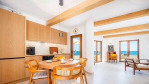 A modern kitchen with wooden cabinets and a dining area with a round table and chairs. - Villa 'Relax Cabrera Miramar' (Colònia de Sant Jordi)