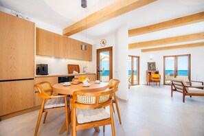 A modern kitchen with wooden cabinets and a dining area with a round table and chairs. - Villa 'Relax Cabrera Miramar' (Colònia de Sant Jordi)